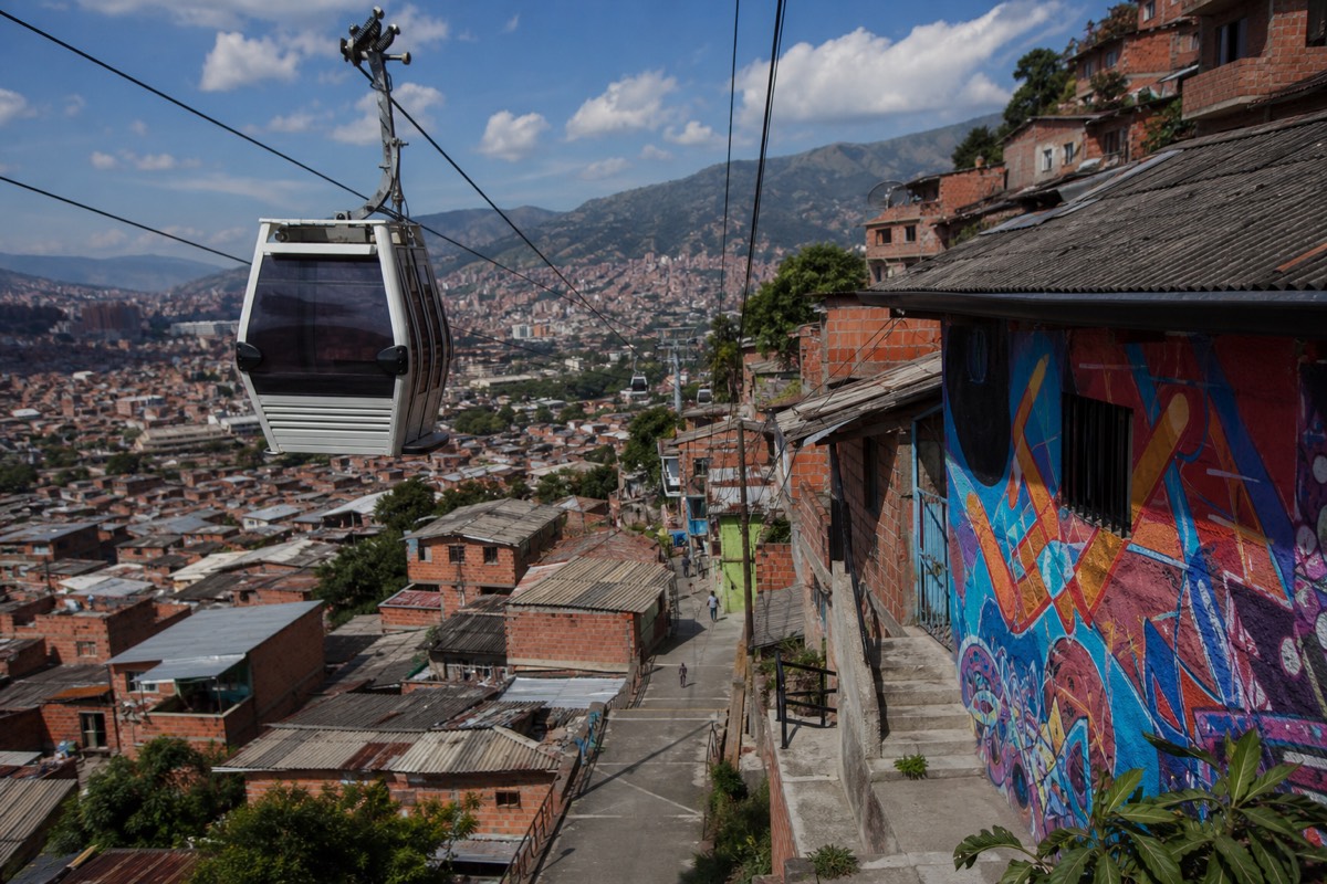 Cable car cabin riding above the dense rooftops of western Medellín toward the San Javier hills