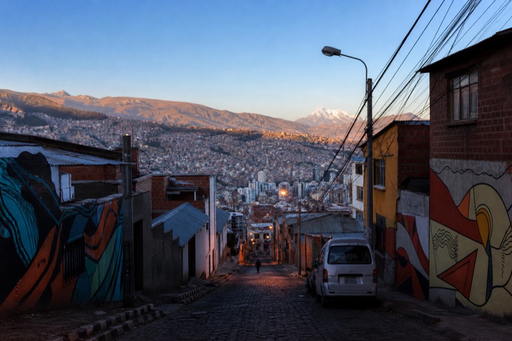 Early morning sunlight spreading across a valley of stacked hillside houses with clear sky and long shadows between the buildings