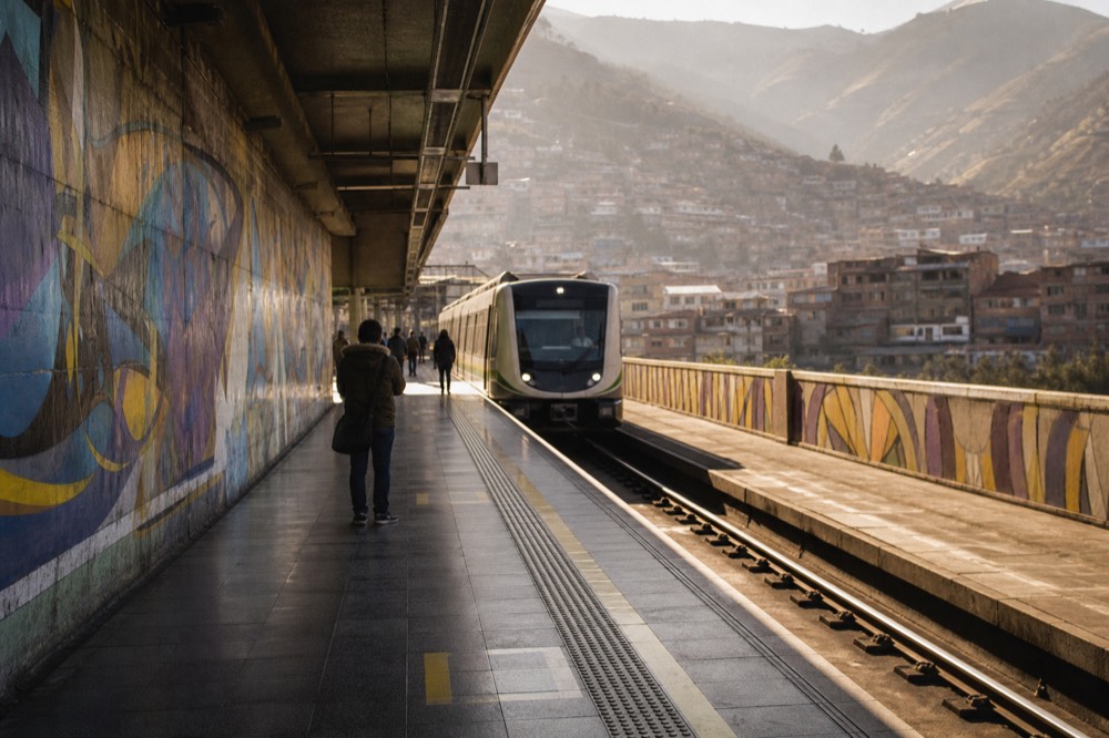 Modern metro platform with a clean train arriving and a handful of distant passengers waiting behind the yellow safety line